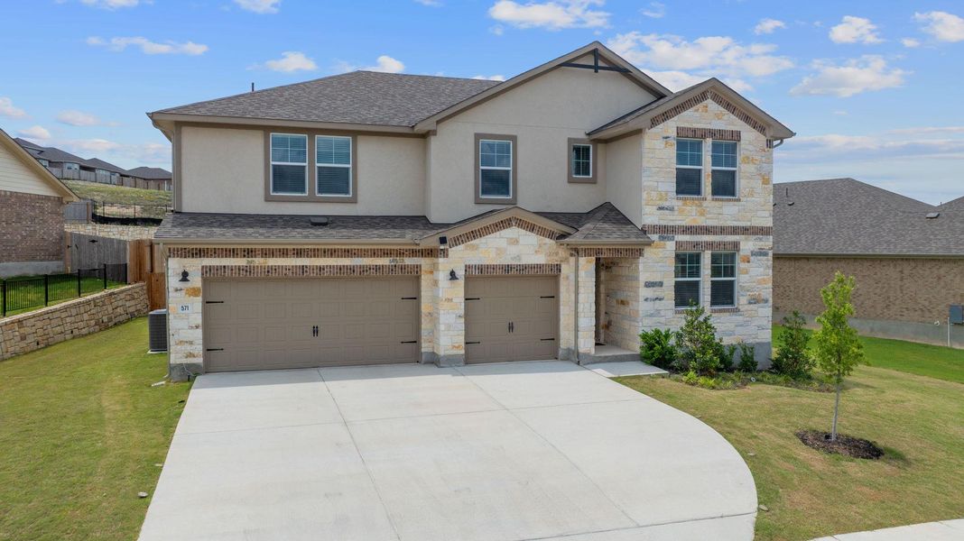 View of front of home featuring fence, concrete driveway, stone siding, a front yard, and a garage View of front of home featuring fence, concrete driveway, stone siding, a front yard, and a garage