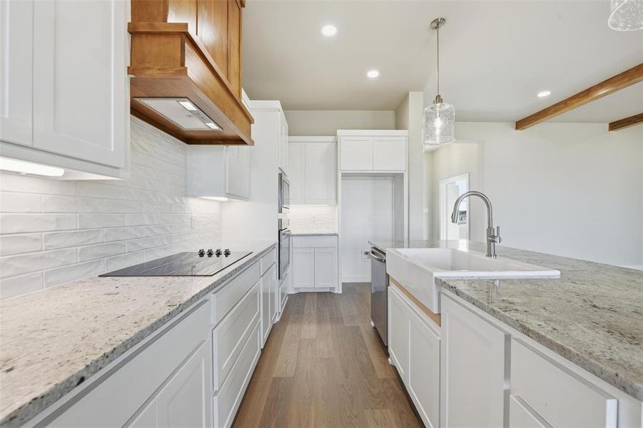 Kitchen with white cabinetry, light stone counters, recessed lighting, dark wood finished floors, and pendant lighting