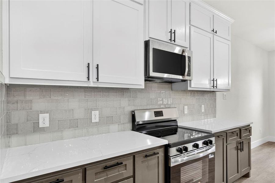 Modern kitchen featuring a large island with a stainless steel sink and dishwasher, white countertops, two-tone cabinetry, and wood-finish flooring