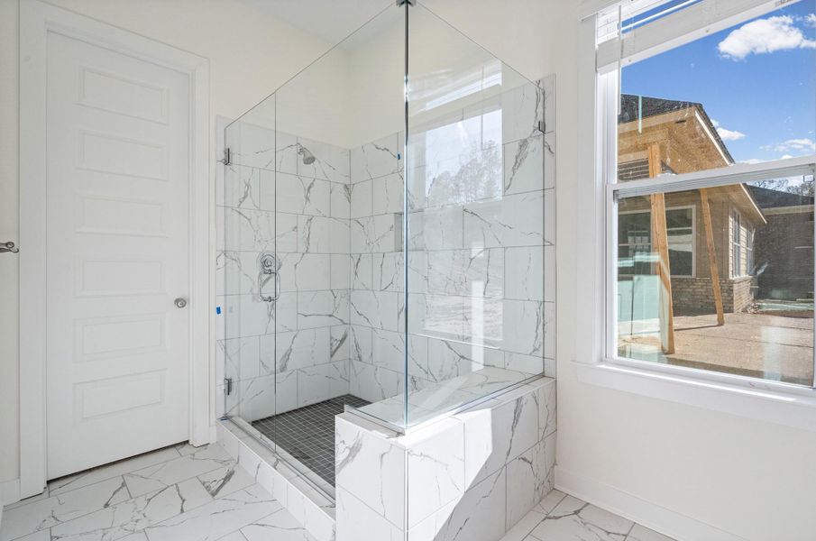 Full bathroom featuring a marble finish shower, healthy amount of natural light, and light marble finish flooring