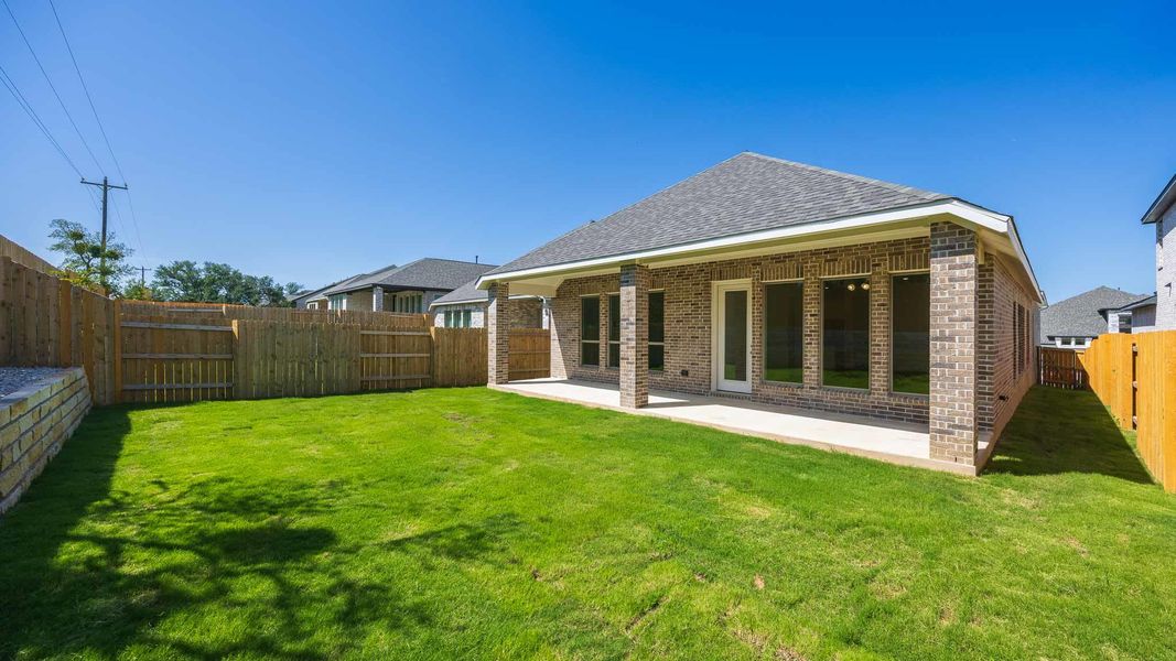 Rear view of house with brick siding, roof with shingles, a fenced backyard, and a patio area Rear view of house with brick siding, roof with shingles, a fenced backyard, and a patio area