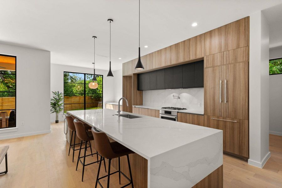 Minimalist design shines with flat-panel wood cabinetry and a dramatic waterfall quartz island.