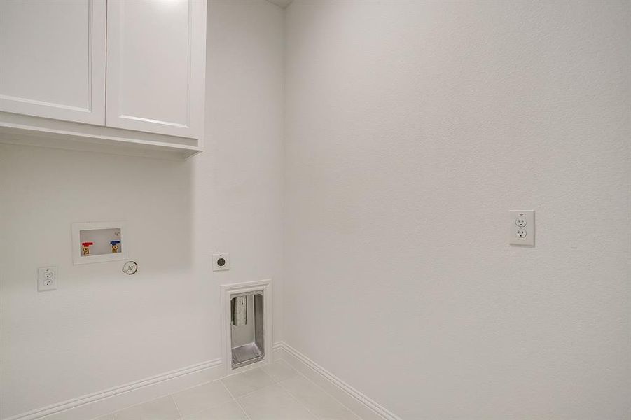 Washroom with cabinet space, washer hookup, electric dryer hookup, and light tile patterned floors