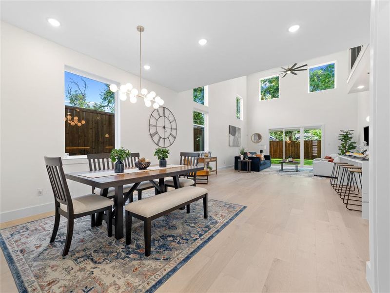 Dining room with recessed lighting, light wood finished floors, a ceiling fan, and a towering ceiling