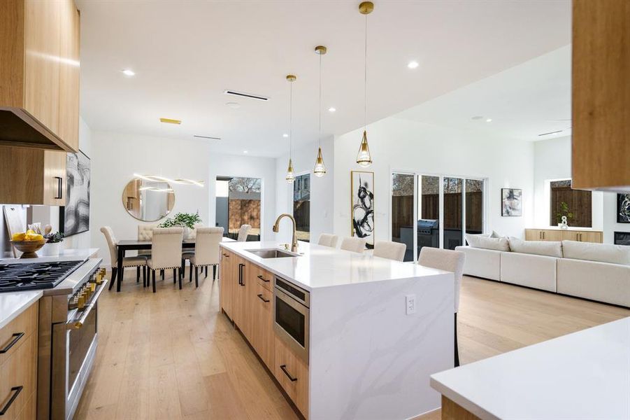 Kitchen with pendant lighting, stainless steel appliances, a kitchen bar, a kitchen island with sink, and sink