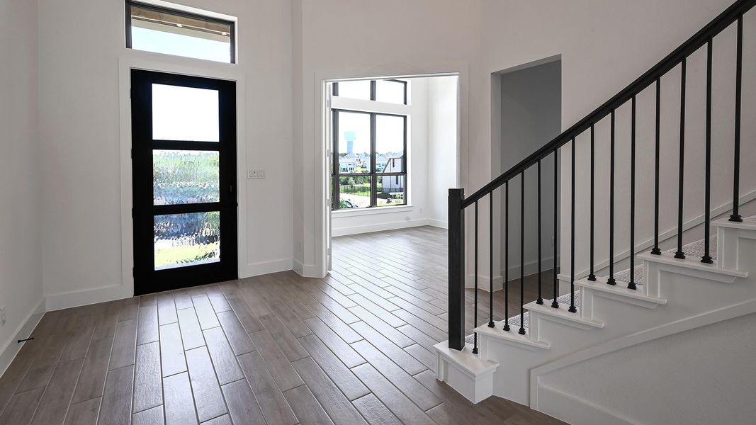 Foyer entrance with stairway, healthy amount of natural light, wood finished floors, and a towering ceiling Foyer entrance with stairway, healthy amount of natural light, wood finished floors, and a towering ceiling