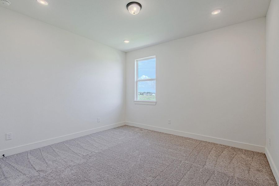 Another sunlit secondary bedroom with soft carpet and neutral tones
