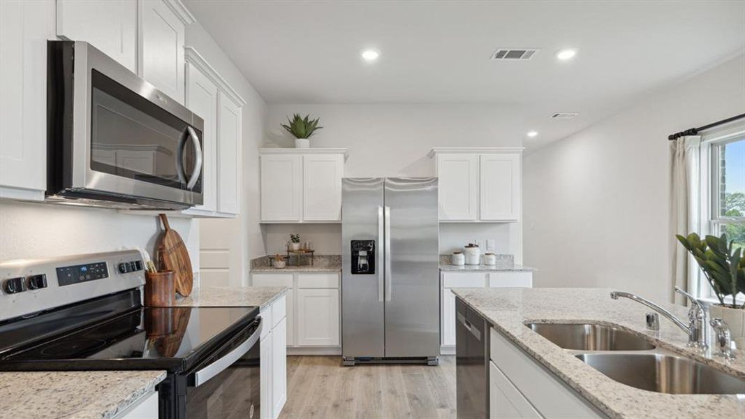 Kitchen with stainless steel appliances, white cabinets, recessed lighting, light wood-type flooring, and light stone counters