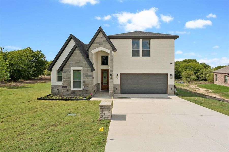 View of front of home with a garage and a front lawn