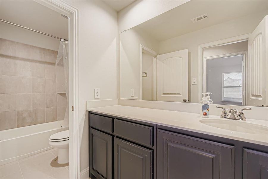 Full bathroom with light tile patterned floors, vanity, and shower / tub combo