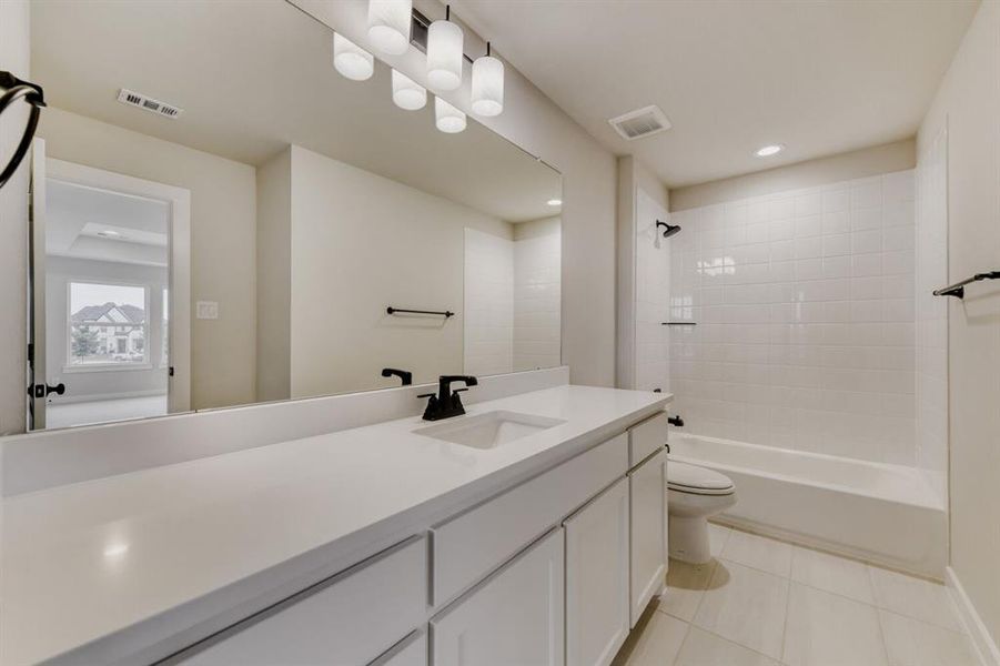 Modern bathroom featuring a white vanity with integrated sink, a large mirror, and matte black fixtures