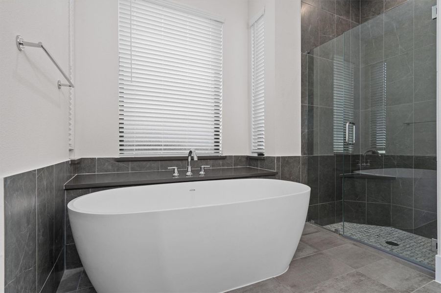 Full bath with a soaking tub, tile walls, a stall shower, and a wainscoted wall Full bath with a soaking tub, tile walls, a stall shower, and a wainscoted wall
