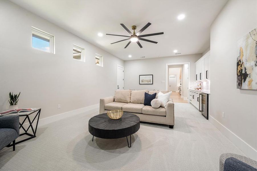 Carpeted living room with beverage cooler and ceiling fan