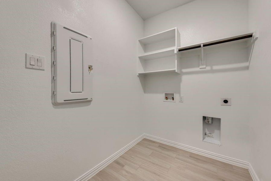 Laundry area with electric panel, washer hookup, hookup for an electric dryer, and light hardwood / wood-style floors