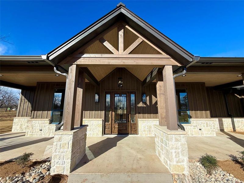 Property entrance with a porch, board and batten siding, and stone siding Property entrance with a porch, board and batten siding, and stone siding