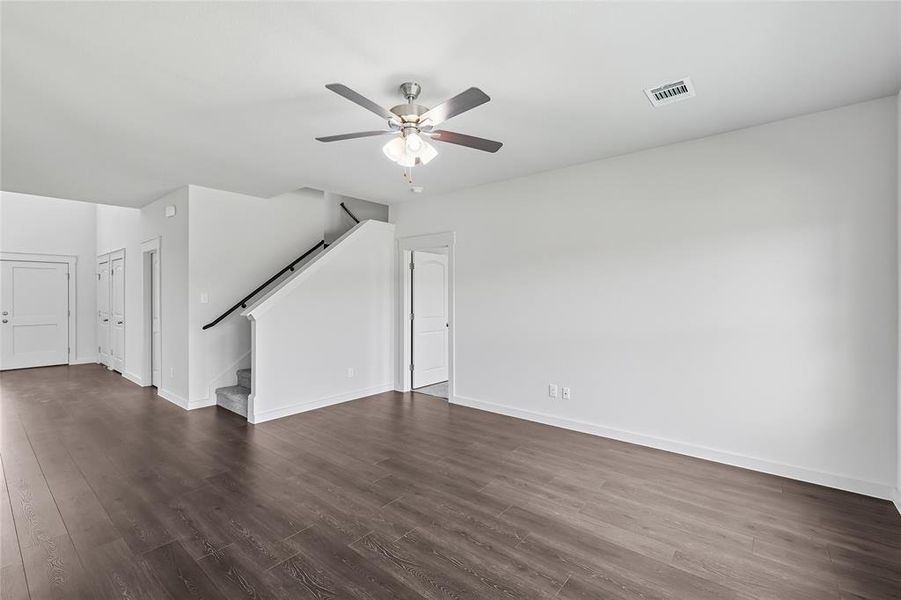 Unfurnished living room featuring dark wood-style floors, stairway, and a ceiling fan Unfurnished living room featuring dark wood-style floors, stairway, and a ceiling fan