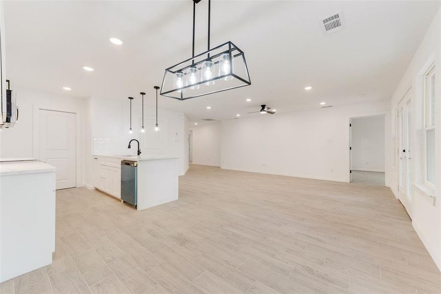 Kitchen featuring pendant lighting, stainless steel dishwasher, white cabinets, and light wood-type flooring