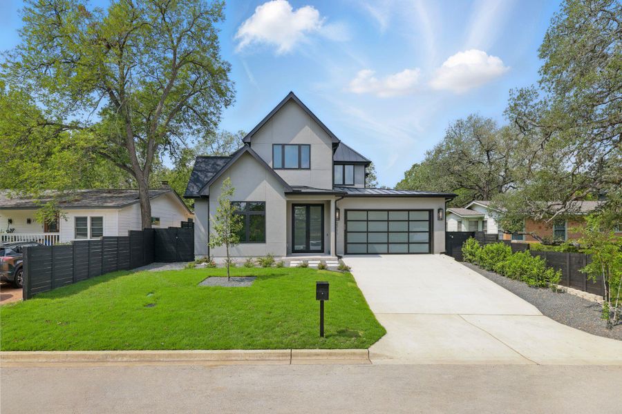 View of front of property with stucco siding, a standing seam roof, driveway, and a metal roof