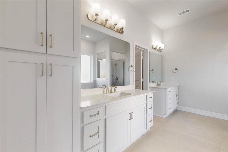 Full bathroom featuring a shower stall, two vanities, and light tile patterned floors