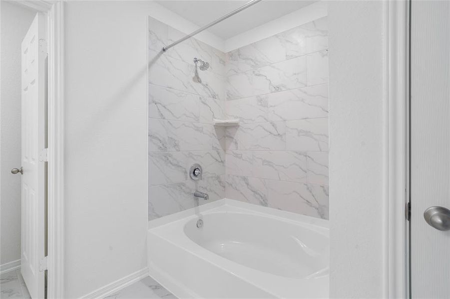 Additional view of the primary bathroom features an oversized tub and shower combination with tile surround with sleek and modern finishes.