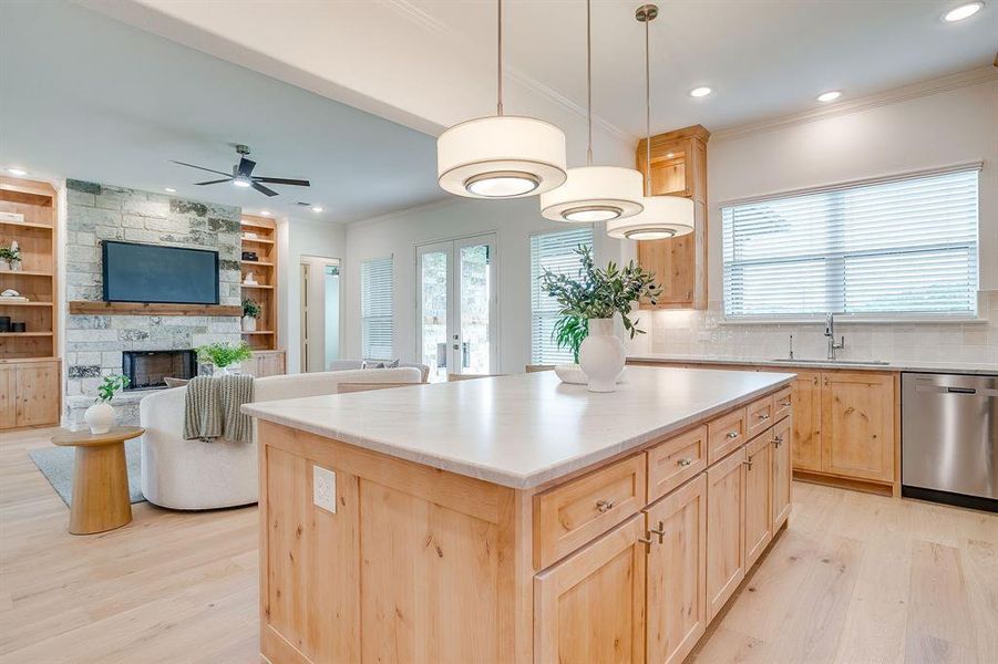 Kitchen with custom Knotty Alder wood cabinets to the ceiling, leathered Quartzite counters, tile backsplash, decorative lighting, ample storage, soft close doors and drawers, and gas cooktop.