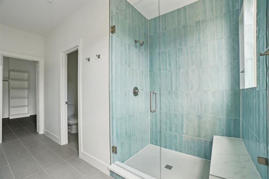 Full bath featuring a shower stall, tile patterned flooring, toilet, and baseboards
