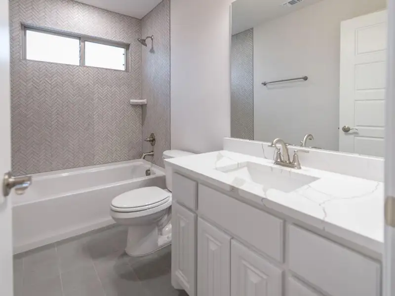 Full bathroom with vanity, tiled shower / bath combo, tile patterned floors, and toilet