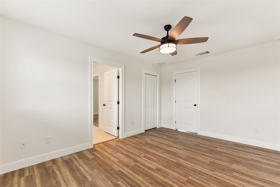 Bedroom 2 bedroom featuring light wood-style flooring, baseboards, visible vents, ceiling fan, and connected bathroom Bedroom 2 bedroom featuring light wood-style flooring, baseboards, visible vents, ceiling fan, and connected bathroom