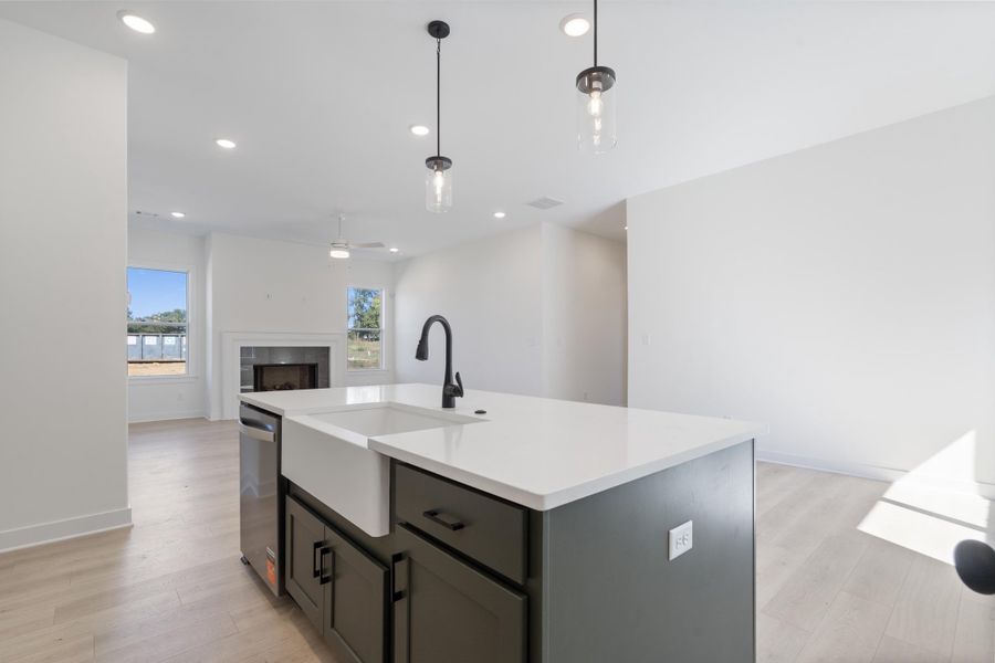 Kitchen island featuring a farmhouse-style apron sink, quartz countertop, and dark cabinetry Kitchen island featuring a farmhouse-style apron sink, quartz countertop, and dark cabinetry