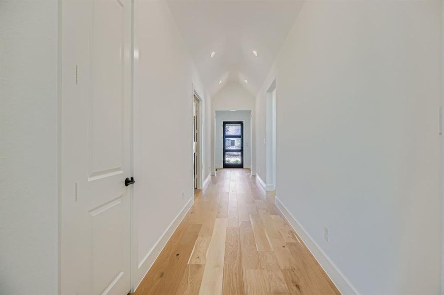 Hall featuring lofted ceiling, light wood-style flooring, and recessed lighting