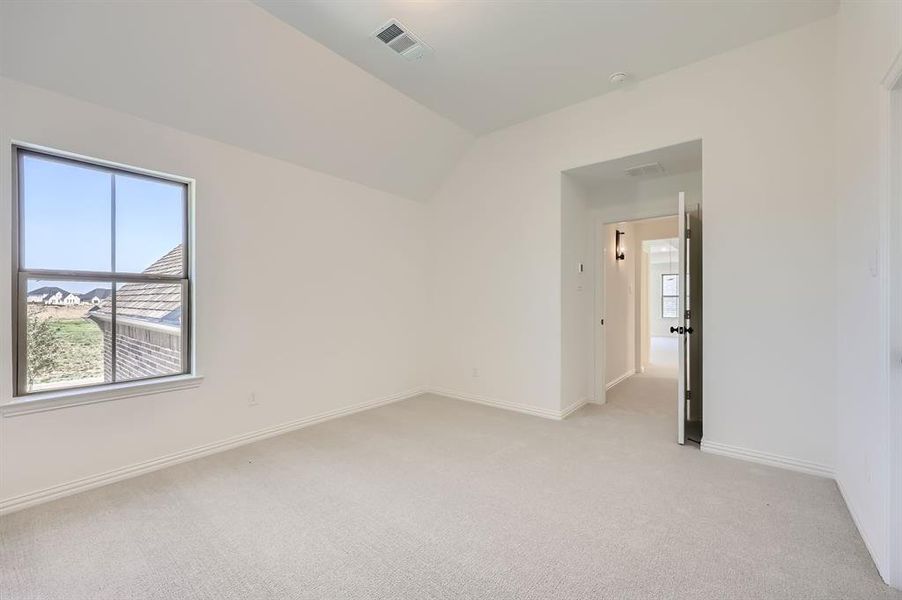 Bedroom with light carpet and vaulted ceiling