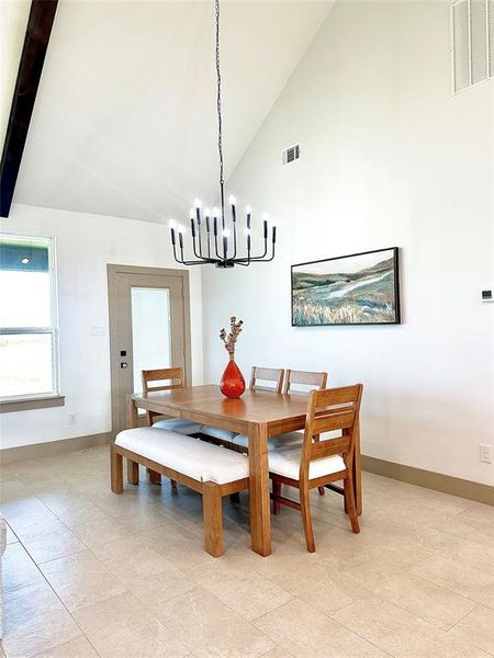 Dining area with high vaulted ceiling, a chandelier, and beam ceiling