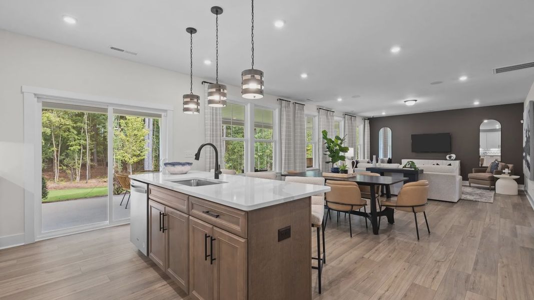 Open concept kitchen island, eat-in breakfast, and family room with abundant windows, in the Jordan Design by DRB Homes