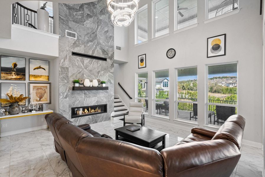 Living area with a premium fireplace, healthy amount of natural light, light marble finish flooring, a high ceiling, and hanging lights