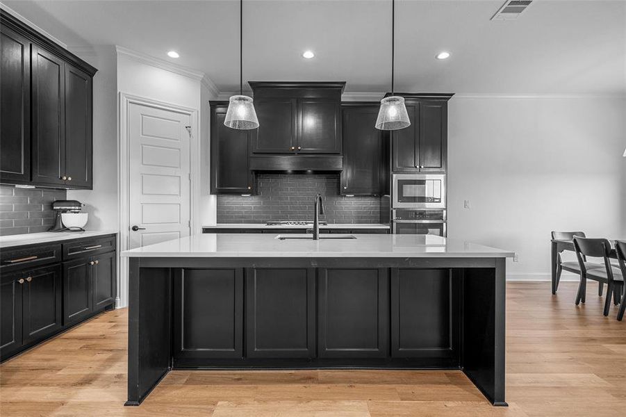 Kitchen featuring dark cabinets, ornamental molding, decorative backsplash, light stone counters, and recessed lighting Kitchen featuring dark cabinets, ornamental molding, decorative backsplash, light stone counters, and recessed lighting
