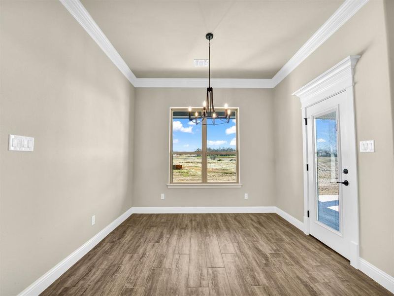 Unfurnished dining area with dark hardwood / wood-style flooring, an inviting chandelier, a wealth of natural light, and crown molding