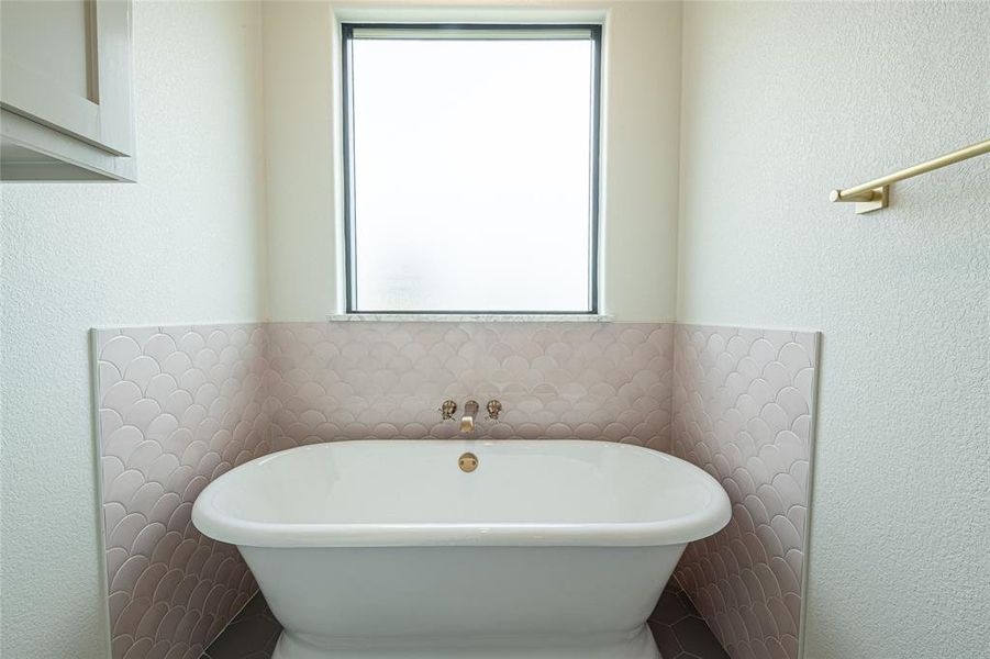 Bathroom featuring a textured wall and a freestanding bath Bathroom featuring a textured wall and a freestanding bath