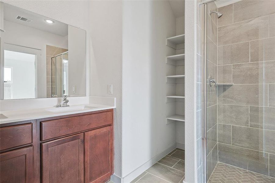 Bathroom featuring vanity, tile patterned flooring, and tiled shower