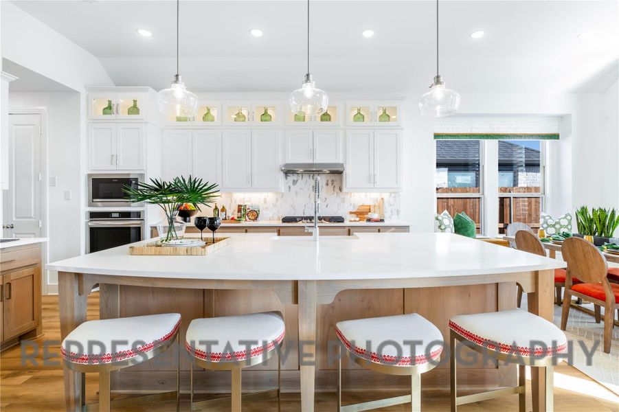 Kitchen with light countertops, appliances with stainless steel finishes, decorative backsplash, and a breakfast bar Kitchen with light countertops, appliances with stainless steel finishes, decorative backsplash, and a breakfast bar