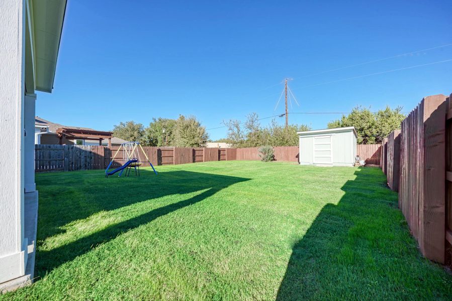 Fenced backyard featuring a storage shed