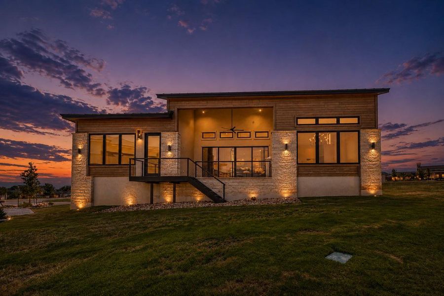 Dramatic sunset skies frame this modern single-story design showcasing stone and timber facade integration.