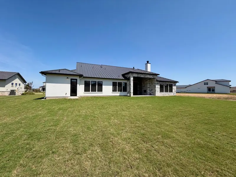 An expansive green lawn stretches out from the modern rear exterior of this home.