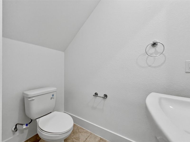 Bathroom with lofted ceiling and light tile patterned flooring