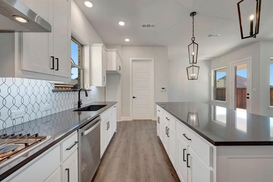 Kitchen featuring white cabinetry, stainless steel appliances, a spacious island, dark wood-style floors, and dark stone countertops