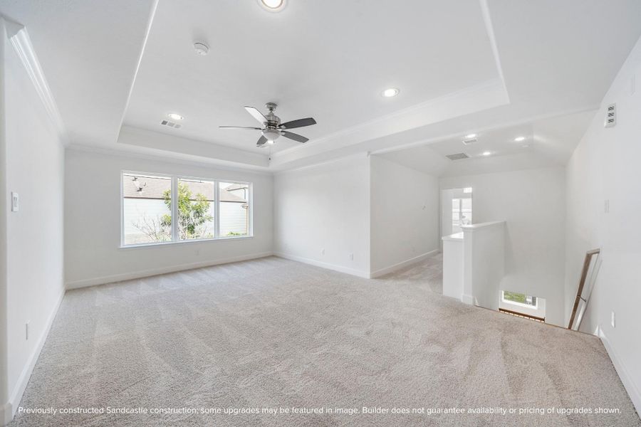 Let the fun begin in this vibrant game room, with a tray ceiling, ceiling fan, and a wall of windows flooding the space with light.