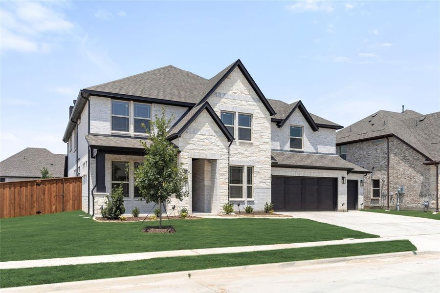 Two-story home with light stone exterior, dark trim, two-car garage, and green front lawn Two-story home with light stone exterior, dark trim, two-car garage, and green front lawn