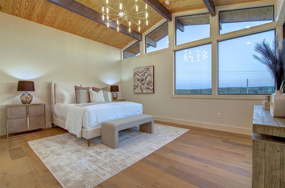 Bedroom with a chandelier, baseboards, multiple windows, wood finished floors, and high vaulted ceiling Bedroom with a chandelier, baseboards, multiple windows, wood finished floors, and high vaulted ceiling