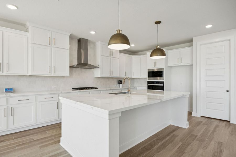 Step into this stunning kitchen featuring a spacious island with pendant lighting, elegant quartz countertops, and a convenient breakfast bar, perfect for casual dining and entertaining.