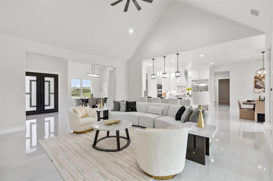 Tiled living room featuring ceiling fan with notable chandelier and high vaulted ceiling.