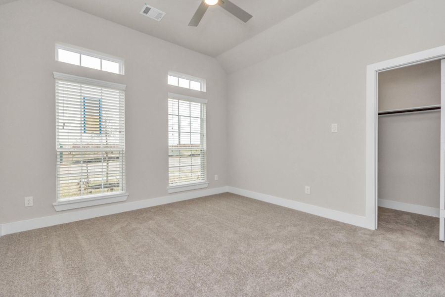 At the forefront, a luxurious bedroom with plush carpeting, custom paint, expansive windows with privacy blinds. Sample photo of completed home with similar floor plan. Actual colors and selections may vary. At the forefront, a luxurious bedroom with plush carpeting, custom paint, expansive windows with privacy blinds. Sample photo of completed home with similar floor plan. Actual colors and selections may vary.